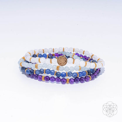 Multi-strand beaded bracelet with white, purple, and blue gemstones and gold-tone charm