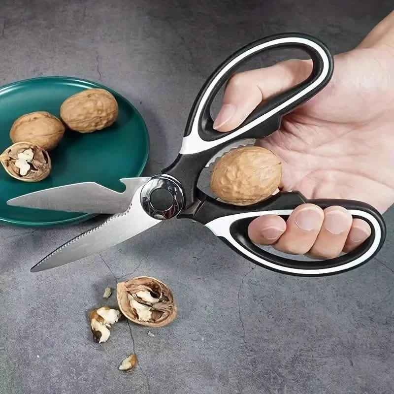 Kitchen scissors with serrated blade held over food, black-and-silver handle