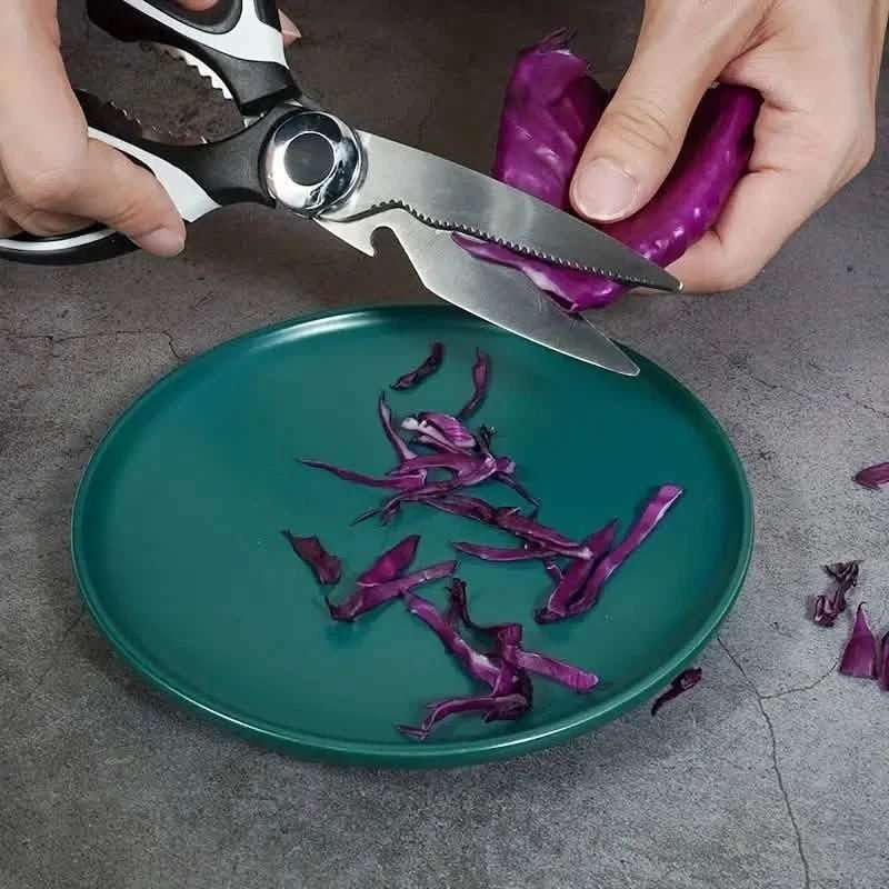 Kitchen scissors cutting a purple vegetable, black-and-silver blades