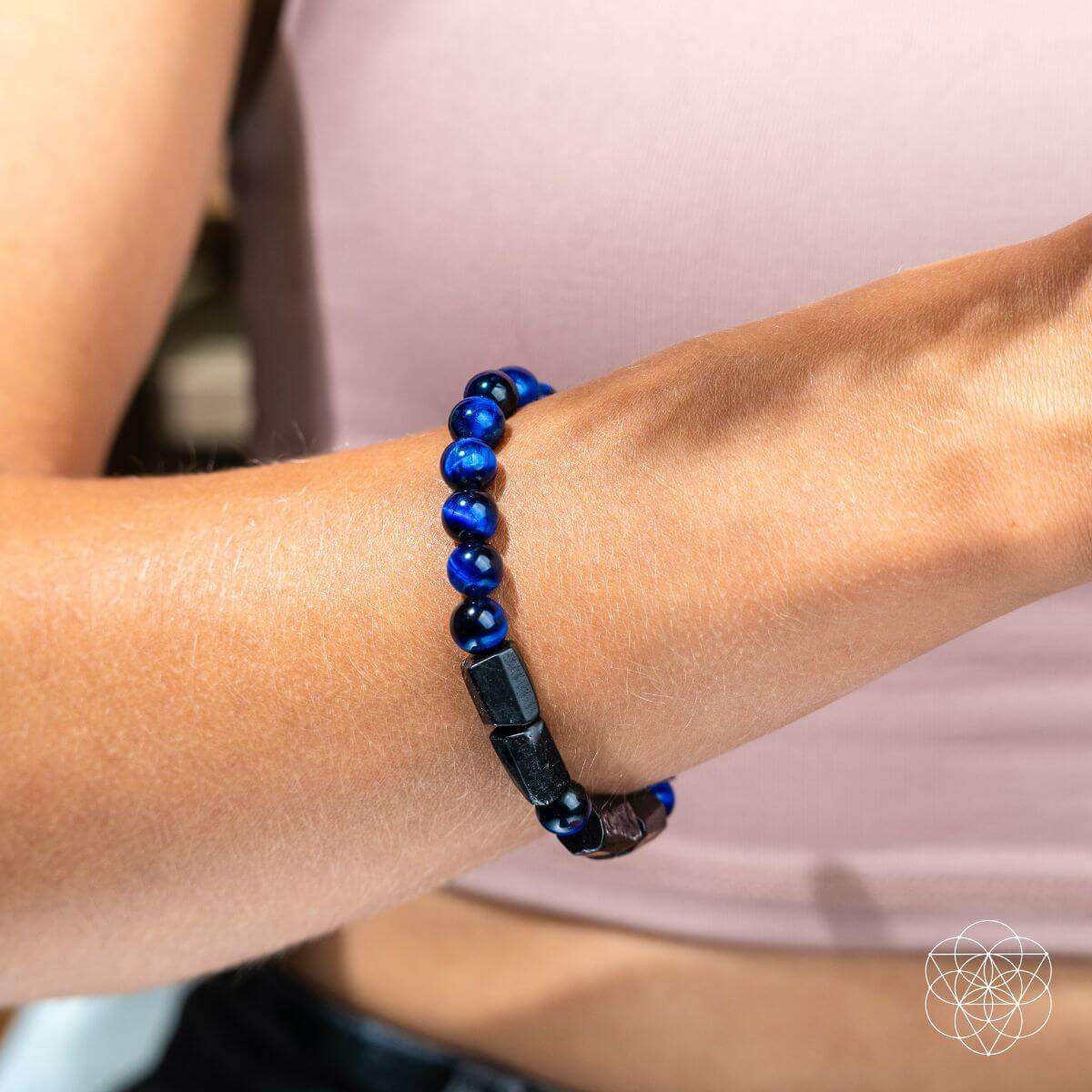Blue-and-black beaded bracelet on wrist with dark geometric bead blocks