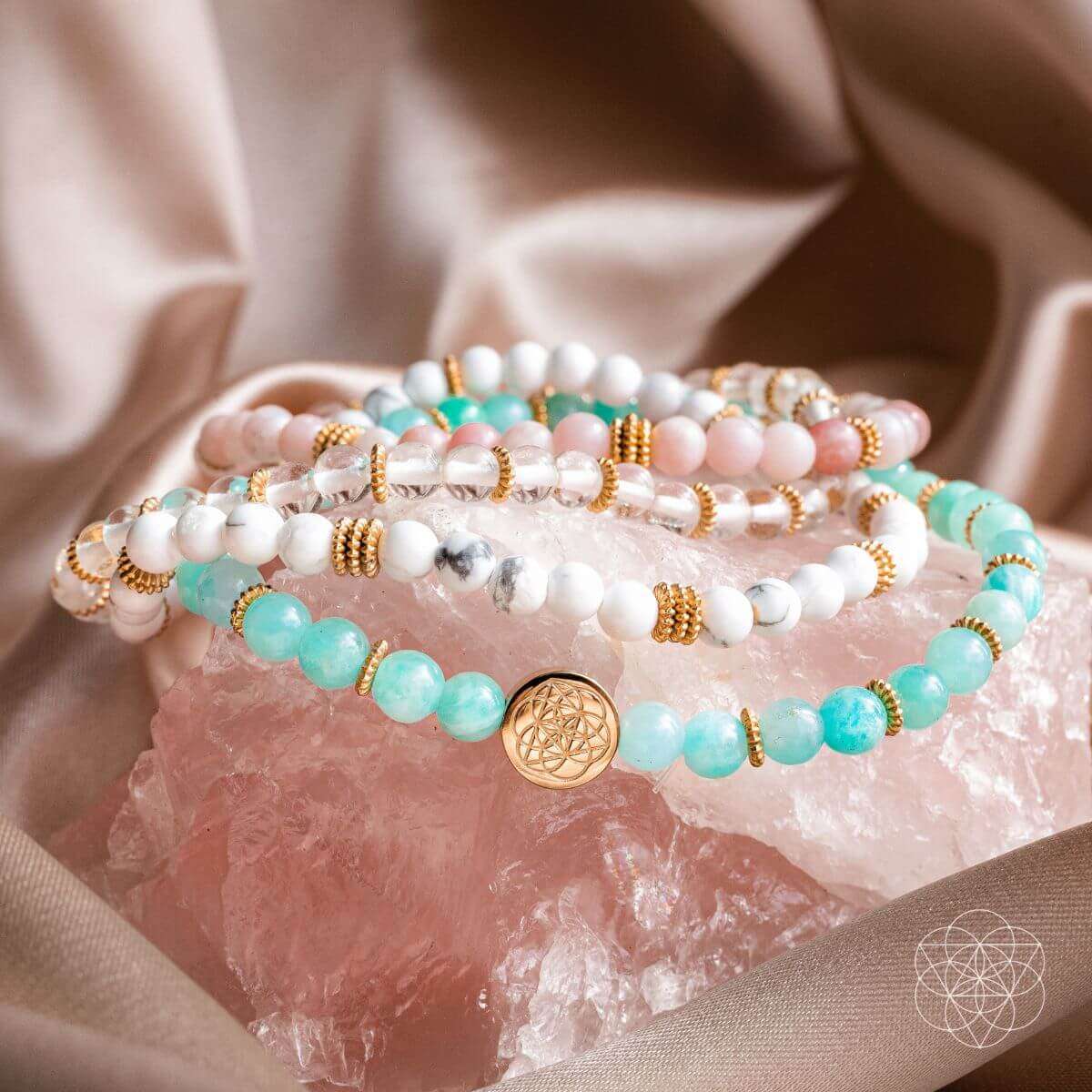 Close-up beaded bracelets with turquoise and white beads and gold flower charm on crystal