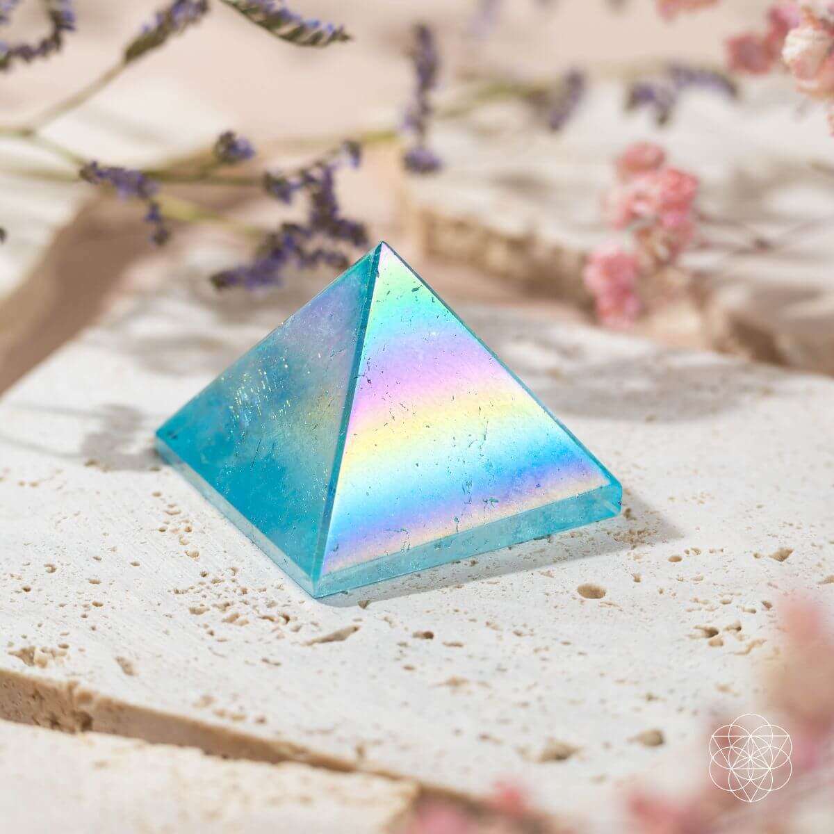 Aqua blue crystal pyramid on white stone with light speckles