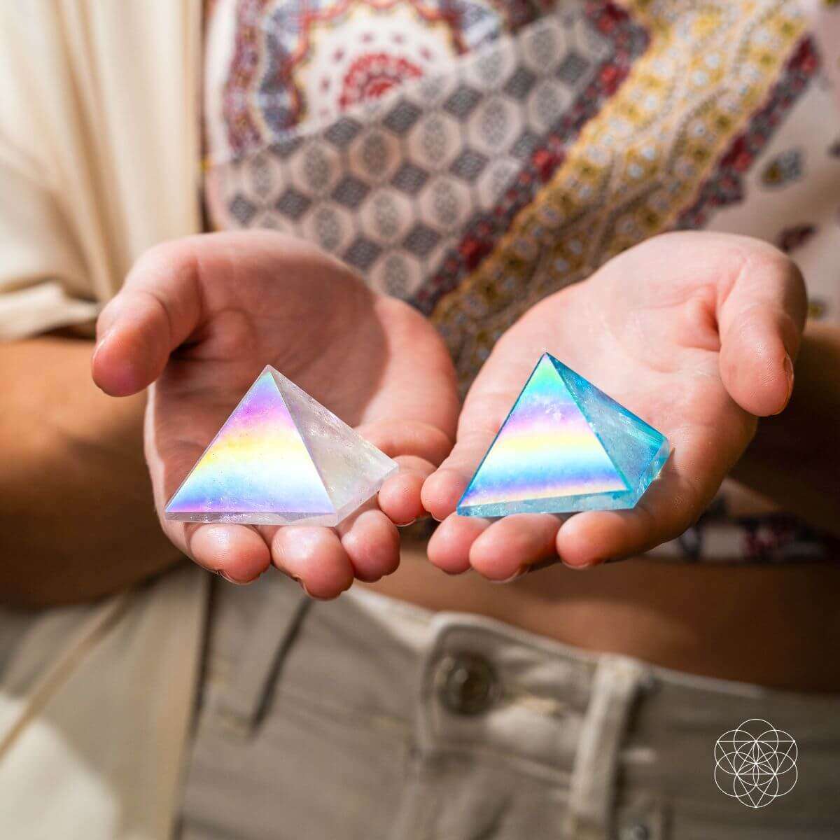 Two crystal pyramids in hands: iridescent angel aura and aqua blue