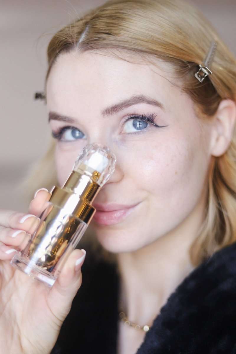 Gold and clear facial serum bottle with white pump; compact glass vial.