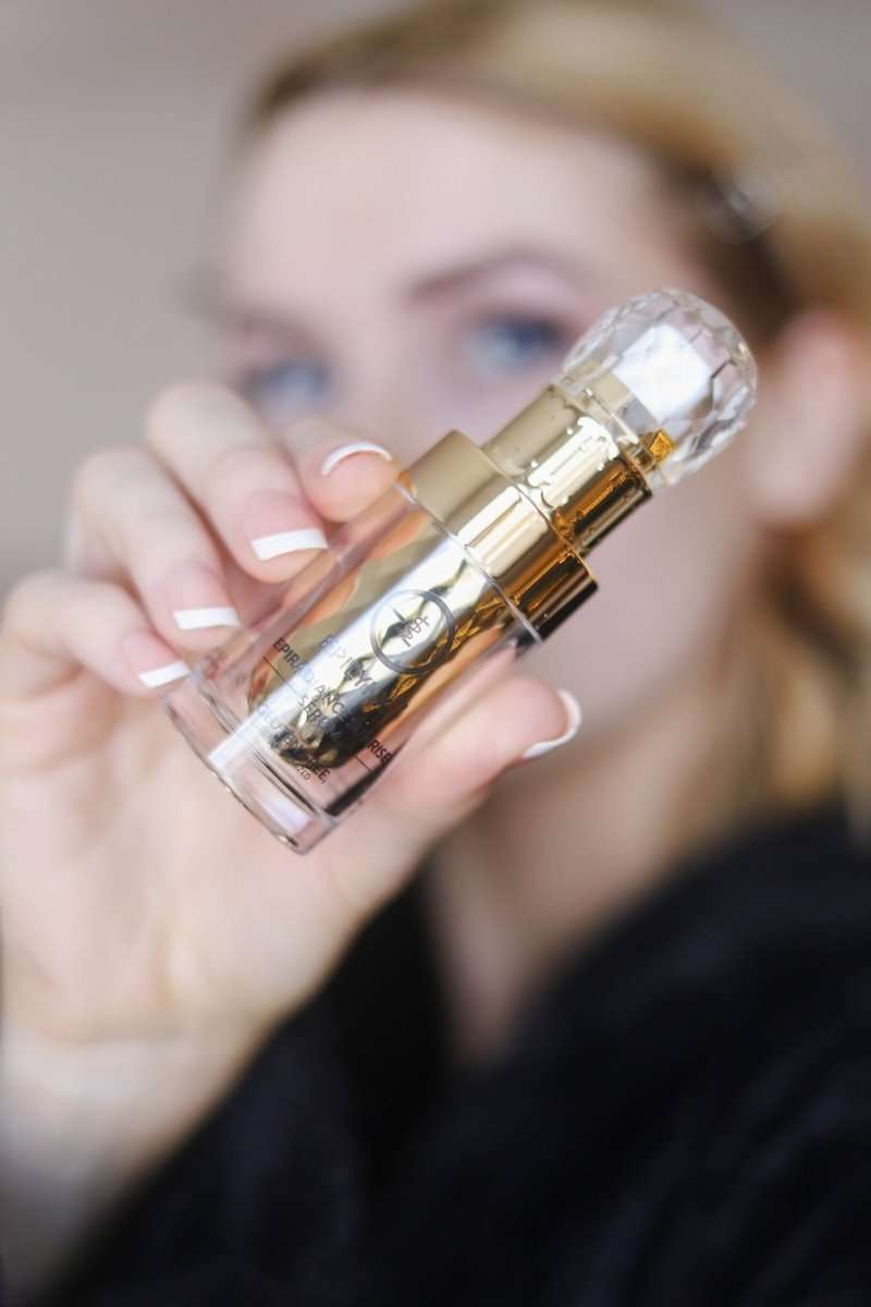 Gold and clear serum bottle in hand with pump, close-up