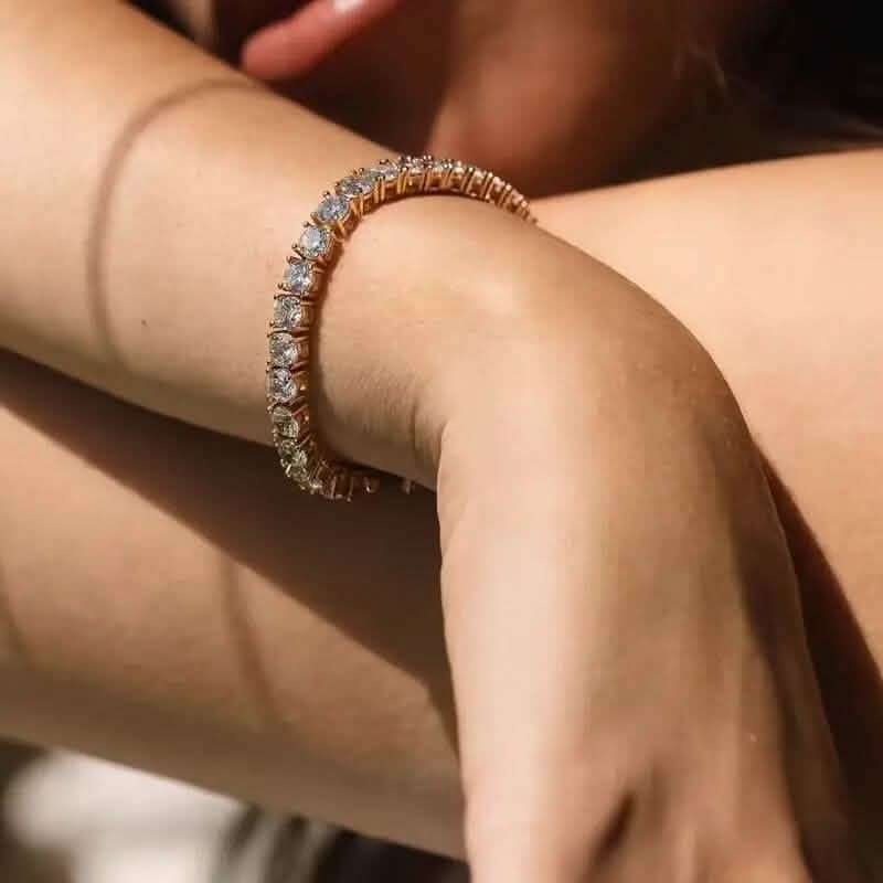 Gold-tone tennis bracelet with single row of clear round stones on wrist