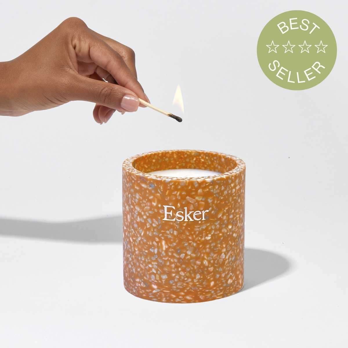 Plantable terracotta candle with speckled texture; lit flame top and match in hand