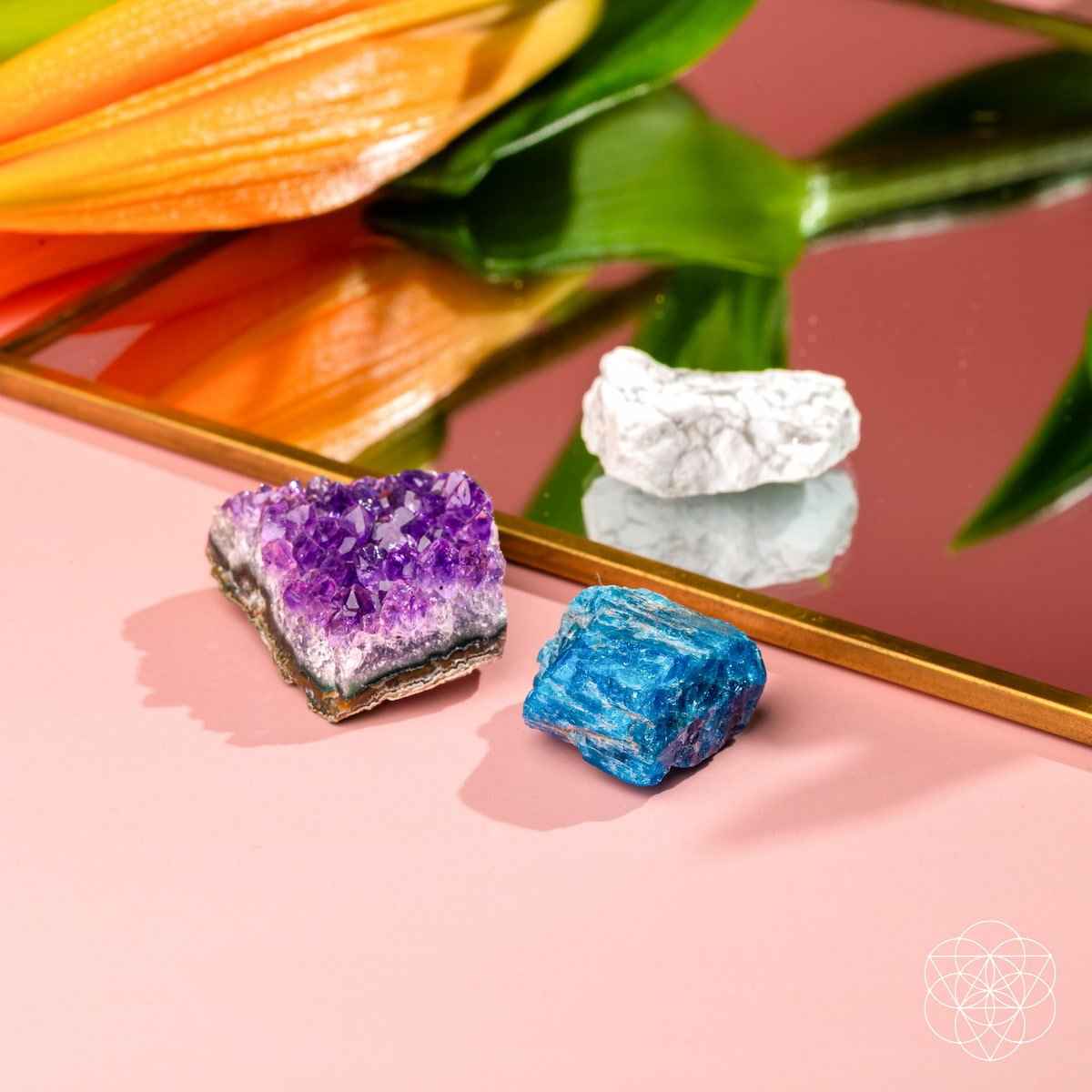 Three crystal stones on a gold tray: purple, blue, and white