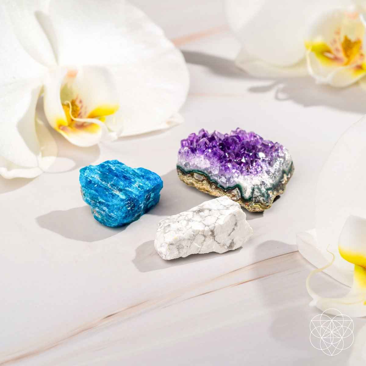 Three crystal stones: blue, purple, and white on a light surface