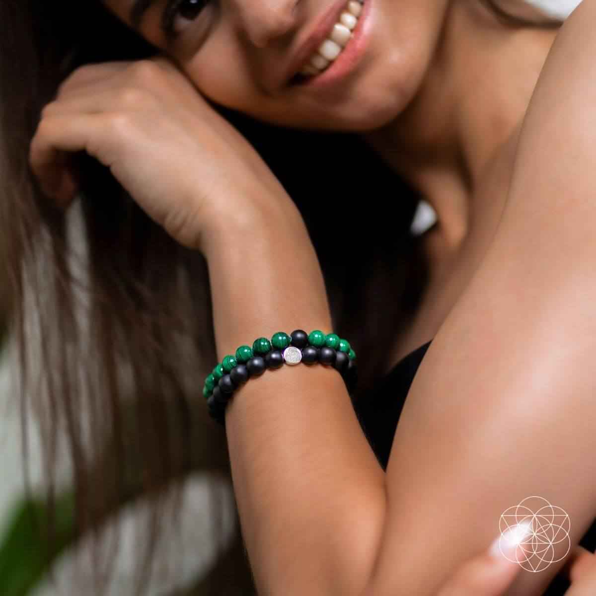 Double bracelet worn on wrist: black beads with green bead bracelet accents