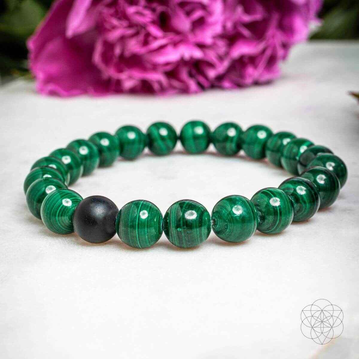 Green beaded bracelet with black beads and subtle geometric charm