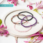 4 beaded bracelet set with black, purple, pink, and pearl-style beads; small disc charms