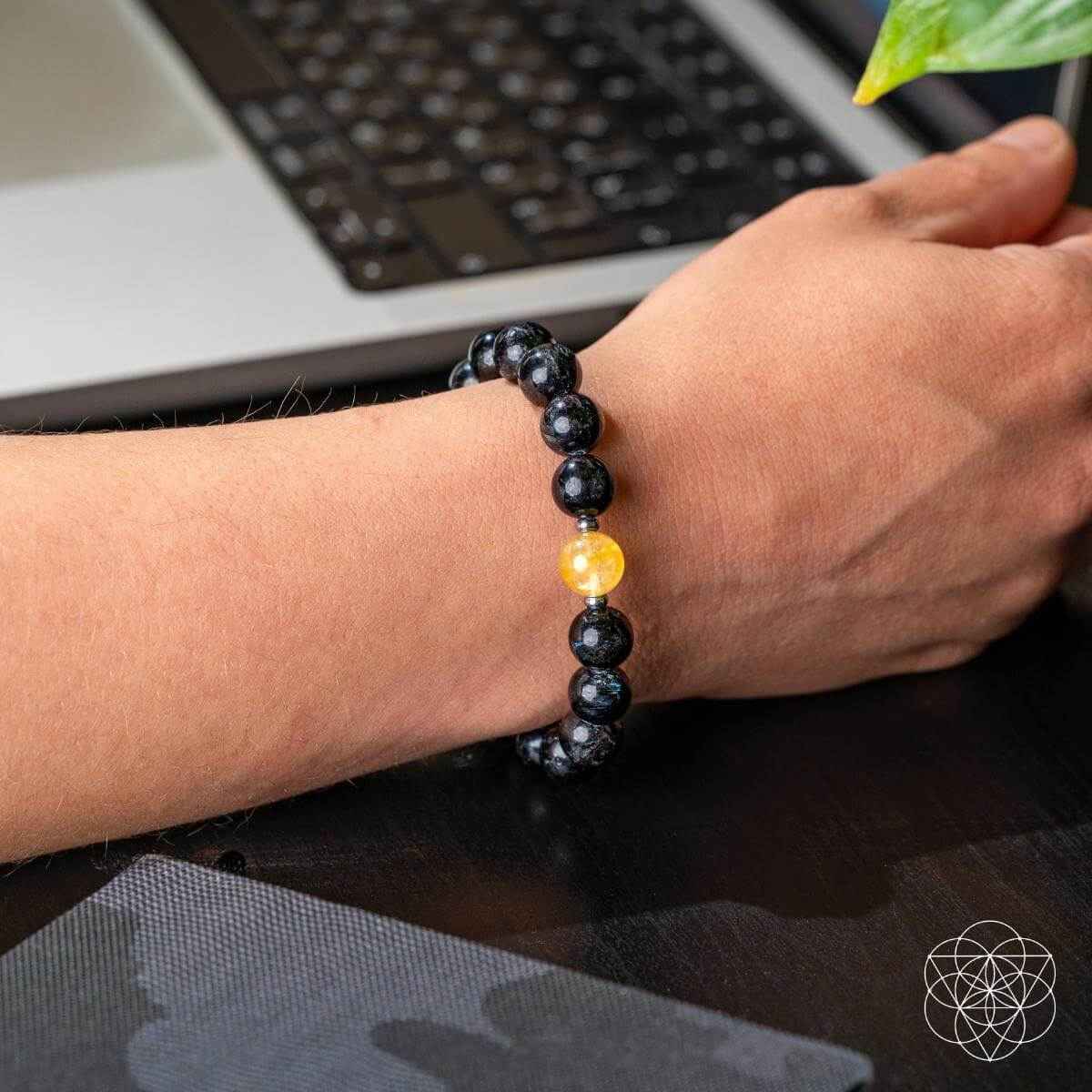 Bracelet on wrist with dark beads and a small yellow center charm