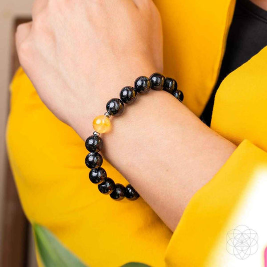 Bracelet on wrist with dark beads and one yellow crystal accent