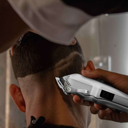 Hand holding silver hair trimmer cutting hair at the side of head