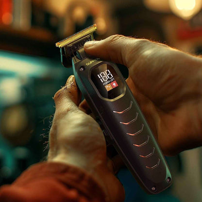 Black electric clipper held in hand, showing gold blade and LCD power display