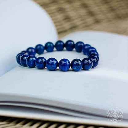 Blue beaded bracelet with round stones, laid flat on a white surface