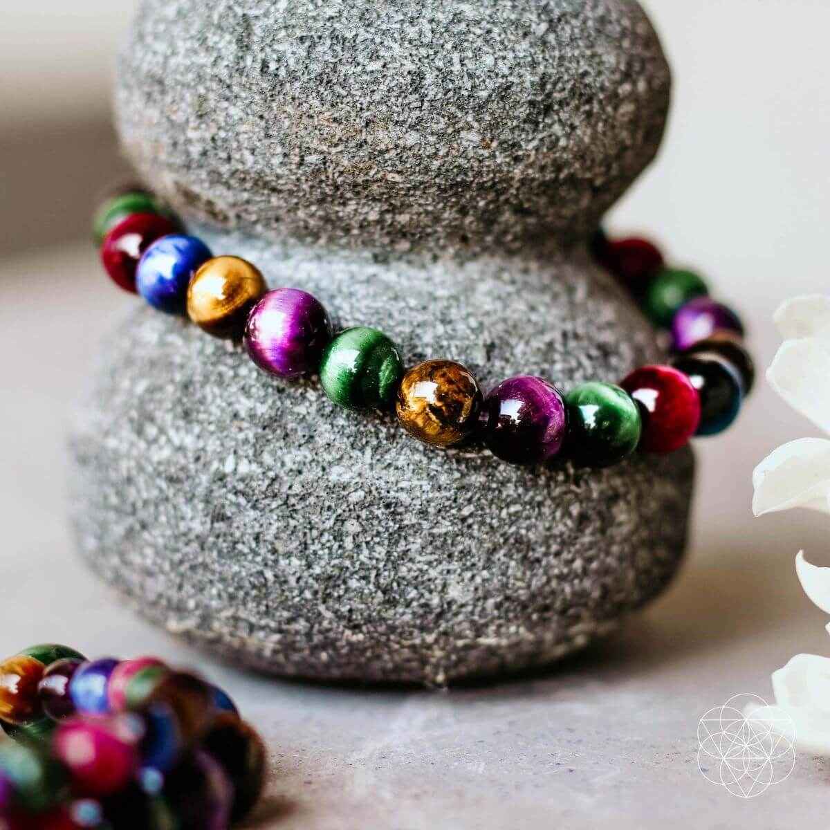 Multicolor beaded bracelet with round gemstone-like beads, shown on a stone pedestal