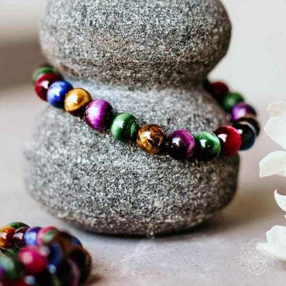 Multicolor beaded bracelet with round gemstone-like beads, shown on a stone pedestal