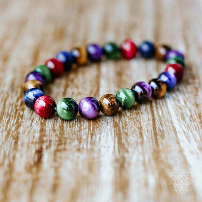Beaded bracelet with multicolor round beads, laid on a light wooden surface