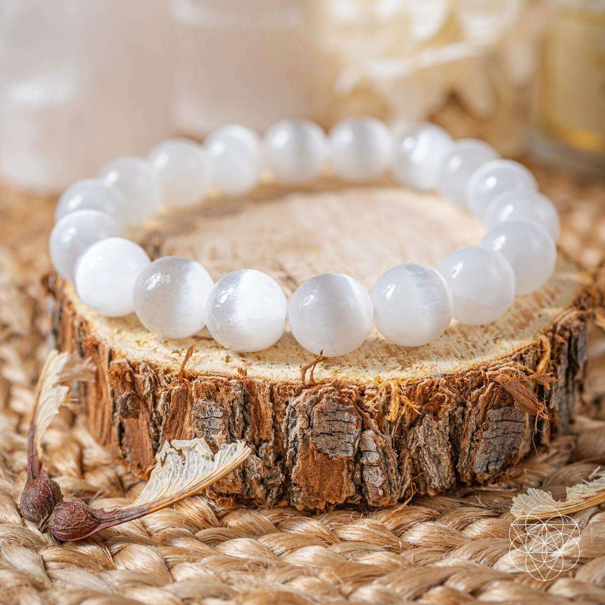 White round-stone bracelet resting on a tree stump