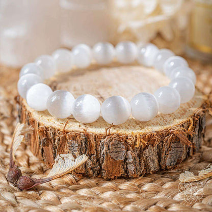White round-stone bracelet resting on a tree stump