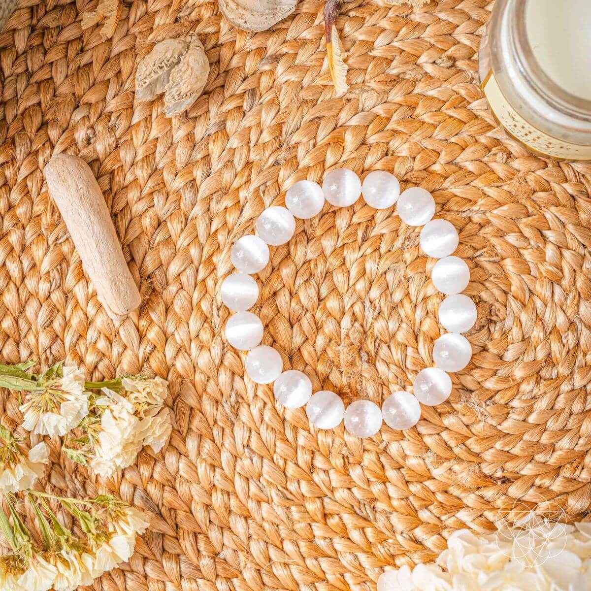 White beaded bracelet lying on woven straw mat