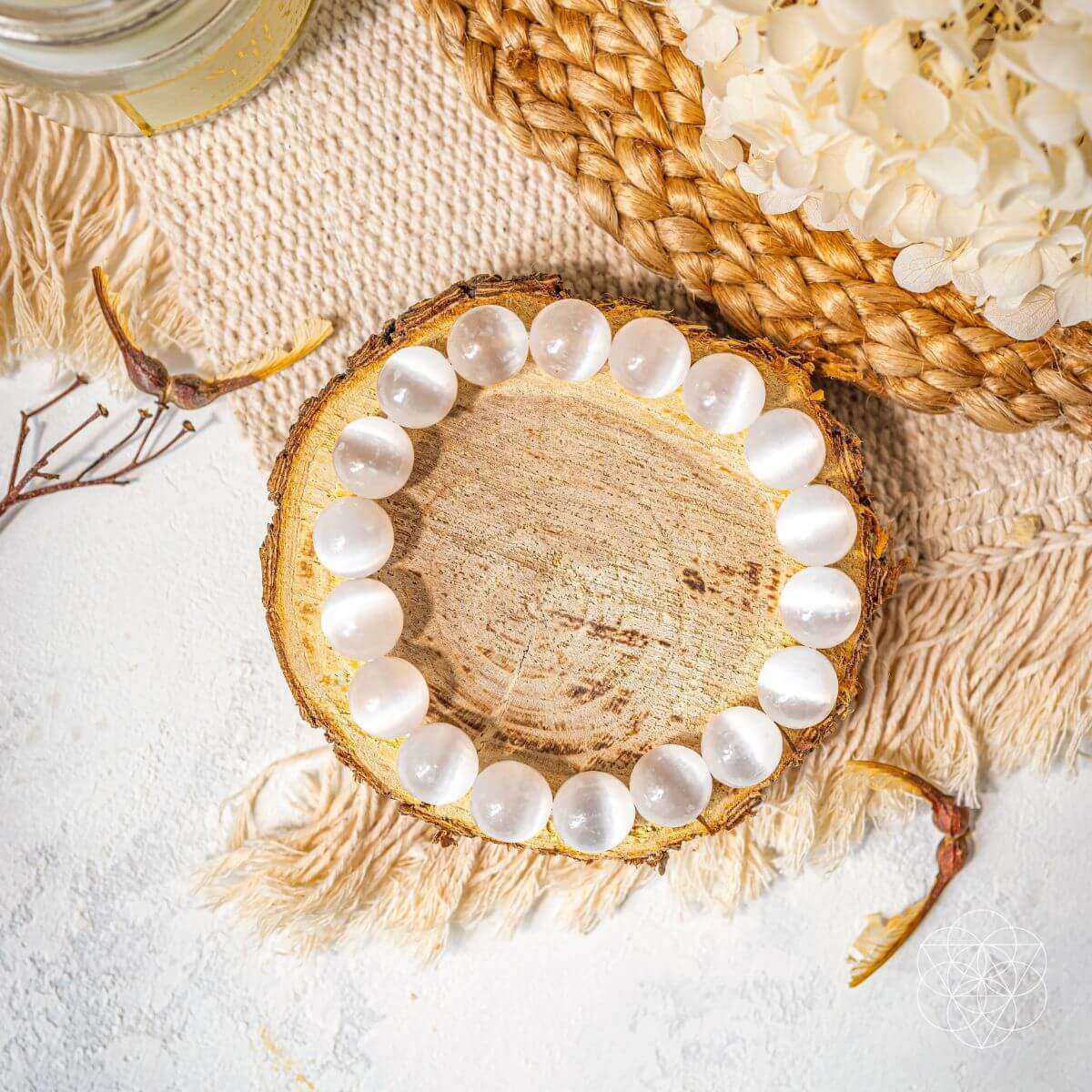 White beaded bracelet with round stones on wooden slice display