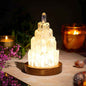 Clear quartz manifestation tower lamp with warm-glowing crystal tower on wooden base