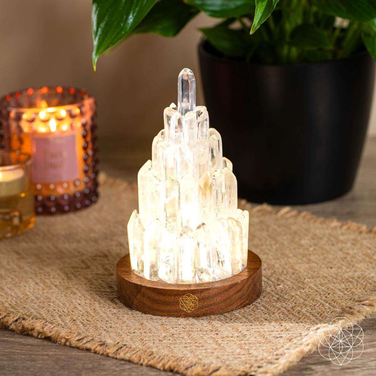 Clear quartz manifestation tower lamp with illuminated crystal stack and round wooden base