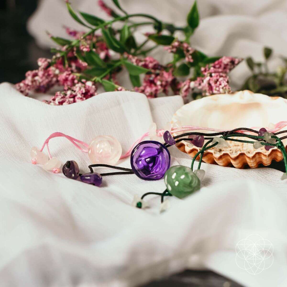 Purple and green beaded anklet with round stone charms on a soft cloth