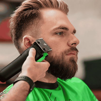 Hair clipper trimming facial hair; black and green clipper with green lever