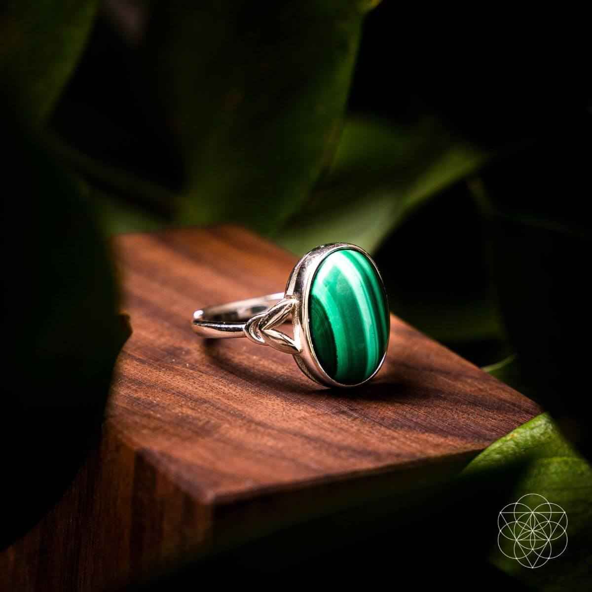 Silver ring with oval green gemstone set in a heart-shaped bezel