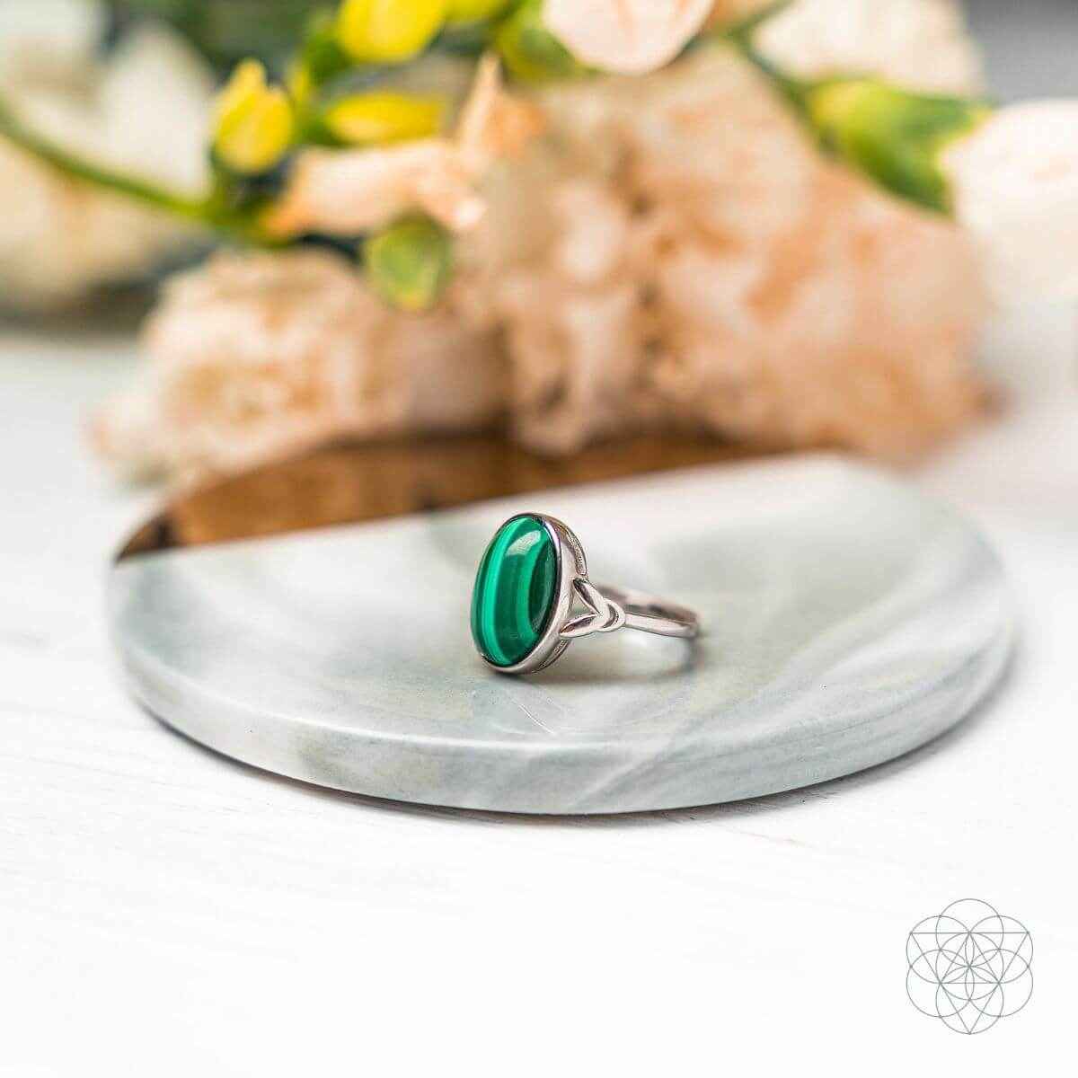 Silver oval green gemstone ring displayed on a white dish