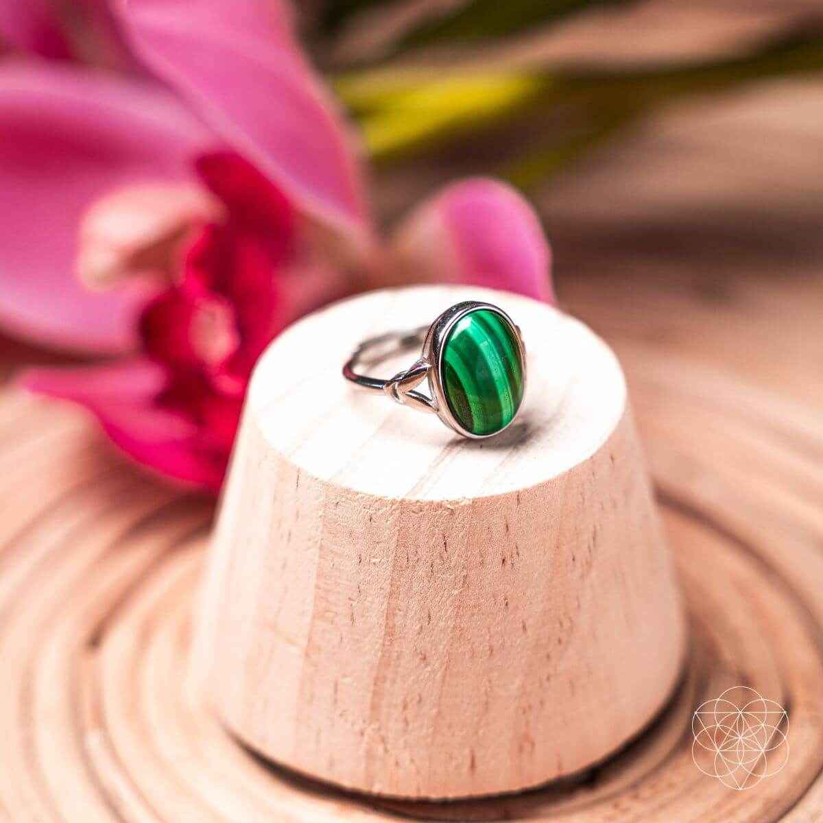 Oval green gemstone ring on a pedestal stand with a silver heart bezel