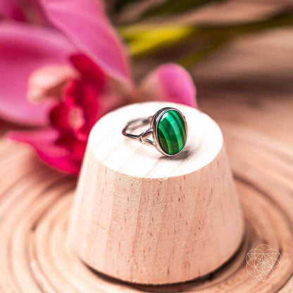Oval green gemstone ring on a pedestal stand with a silver heart bezel