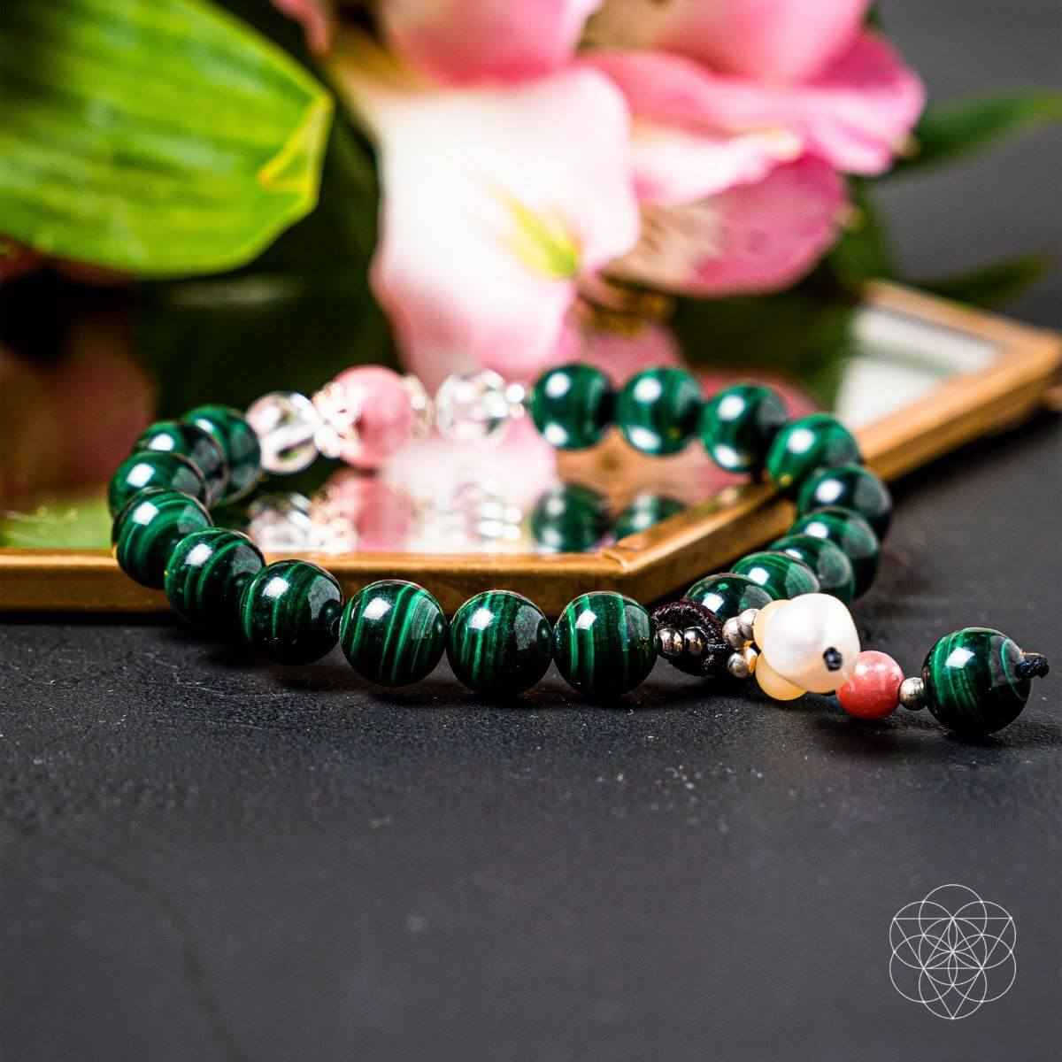 Green beaded bracelet with pink accents, white bead, and dangling heart charm