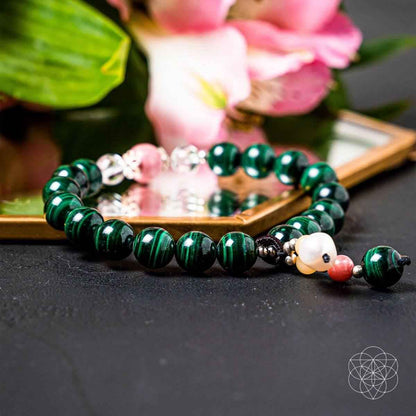 Green beaded bracelet with pink accents, white bead, and dangling heart charm