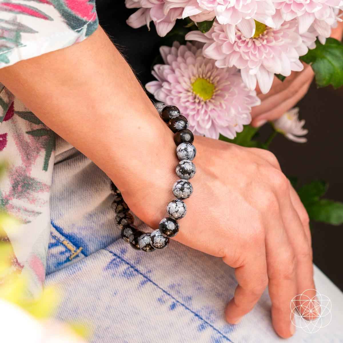 Snowflake obsidian beaded bracelet on wrist, black and gray speckled round beads