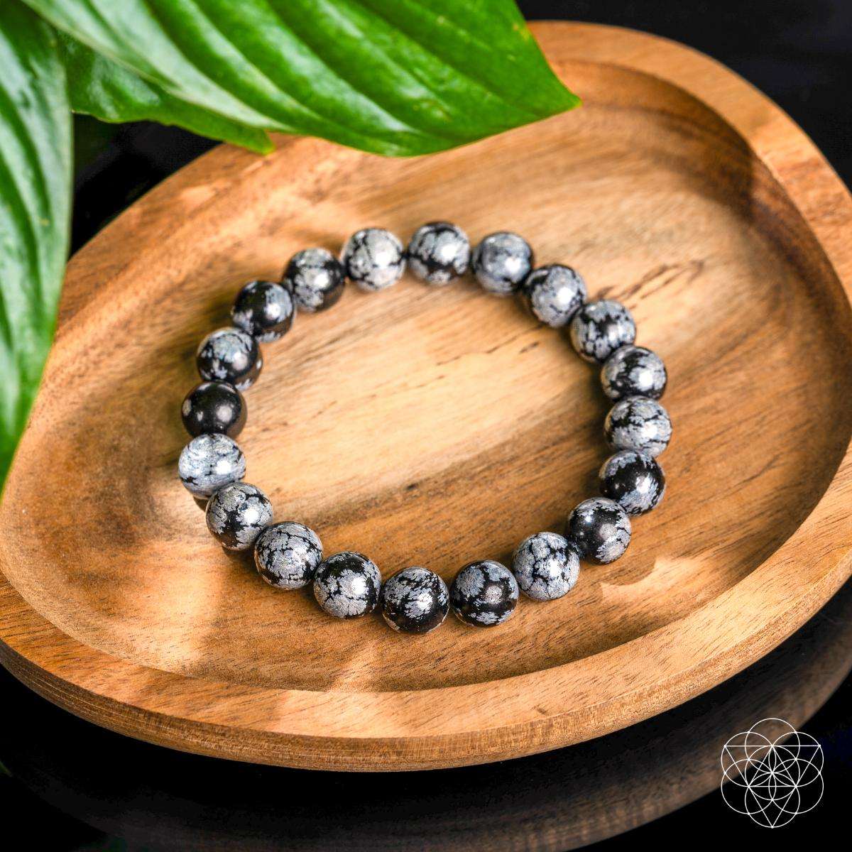 Snowflake obsidian beaded bracelet with black and gray speckled round stones on dish