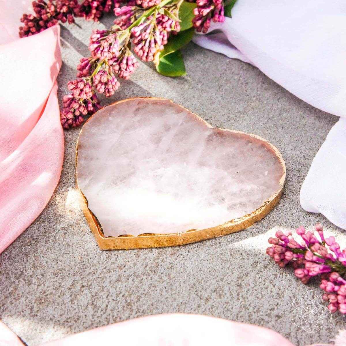 Pink heart-shaped marble coaster with gold rim on a stone surface
