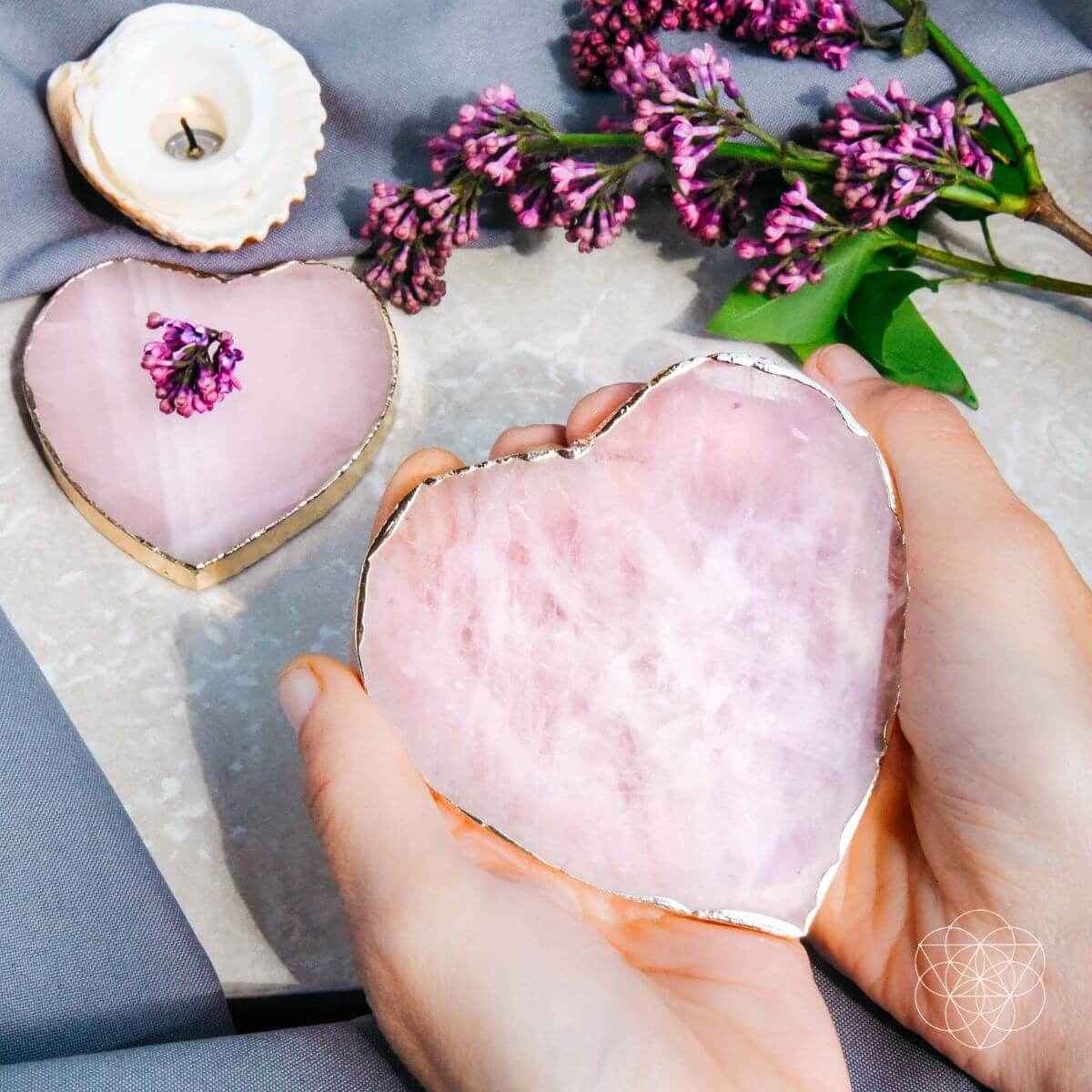 Pink heart-shaped marble coaster with gold rim, held in hand; set of 2