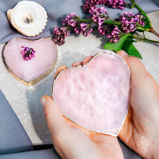 Pink heart-shaped marble coaster with gold rim, held in hand; set of 2