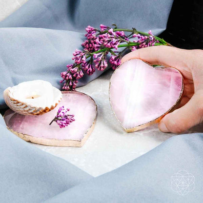Heart-shaped pink marble coasters with gold rims, two shown on fabric table