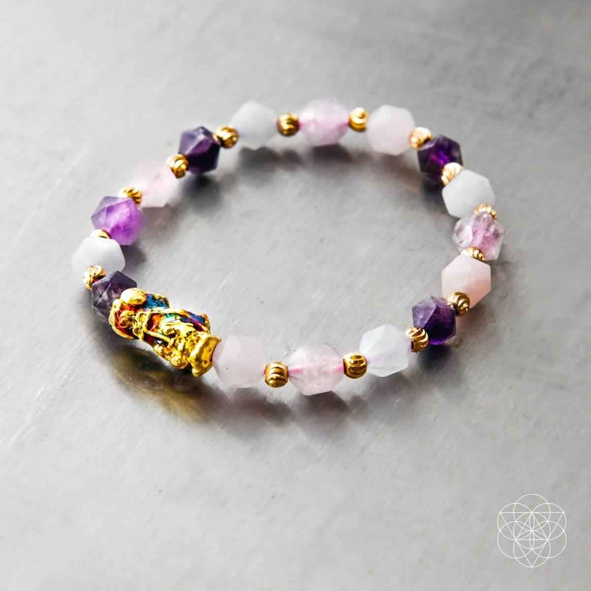 Beaded prosperity bracelet flat lay, purple and pink beads with gold spacers and charm