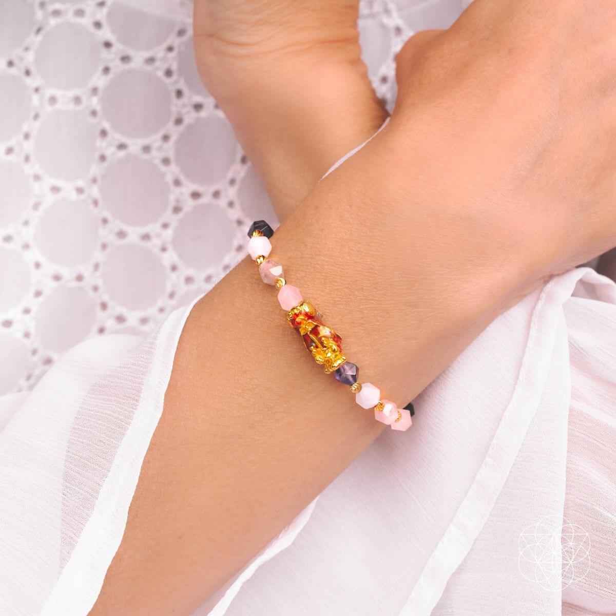 Beaded prosperity bracelet on wrist, pink and purple stones with gold centerpiece charm