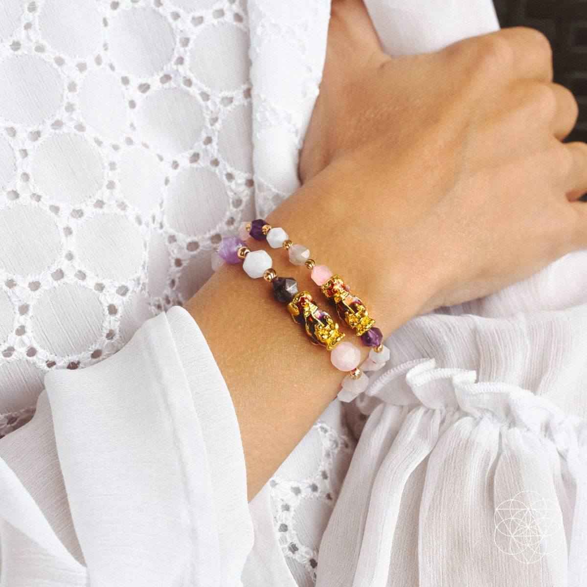 Beaded prosperity bracelet worn on wrist, purple beads with gold charms and pink accents