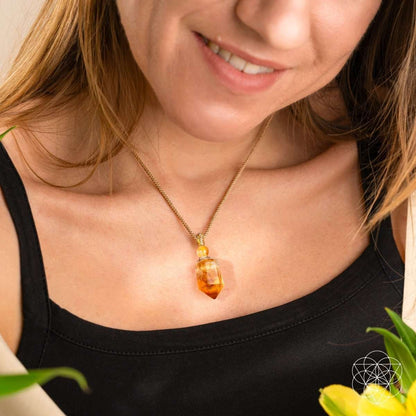 Gold-tone pendant necklace with amber teardrop crystal resting on the collar