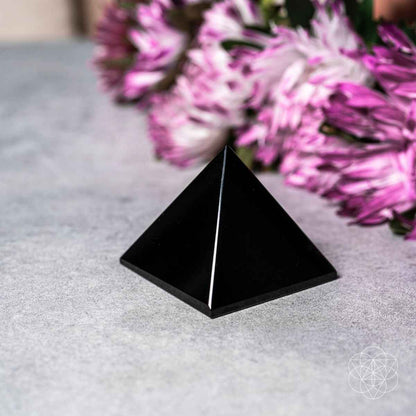 Black pyramid crystal figurine standing on a smooth surface