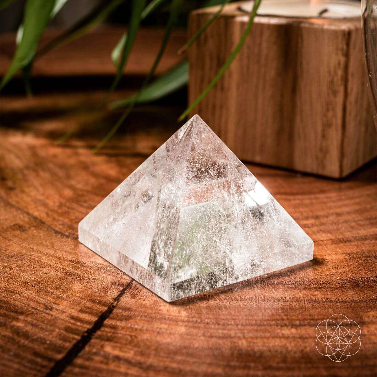 Clear quartz pyramid figurine with faceted sides on wood